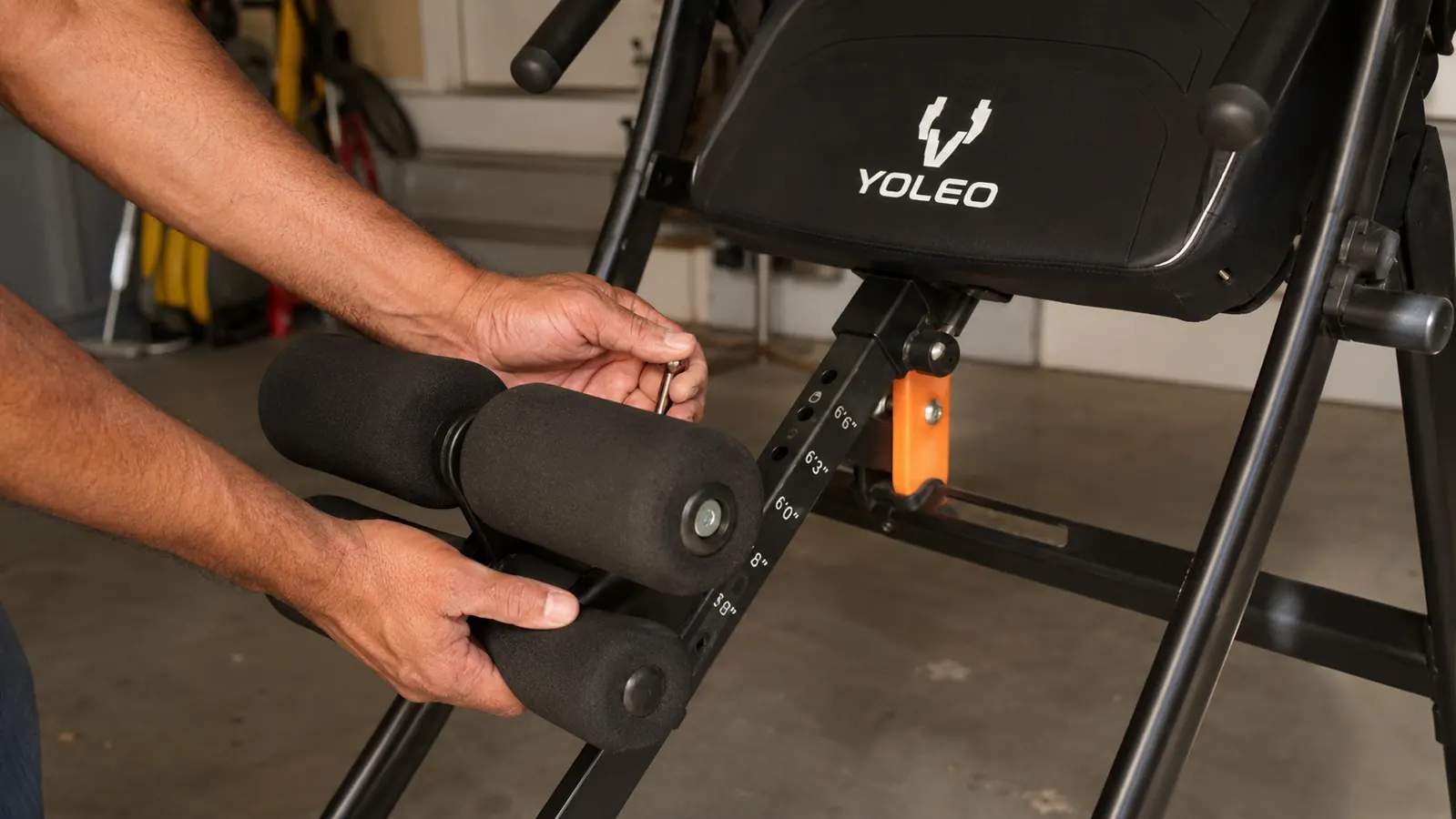 Close-up of hands adjusting the ankle lock and height pin on the YOLEO inversion table